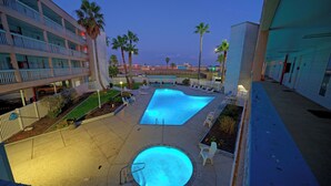 A hotel pool area with a swimming pool, lounge chairs, and palm trees. - Private Balcony w/ Ocean View Pool & Hot Tub Access Ocean Echo by Avantstay (Corpus Christi)