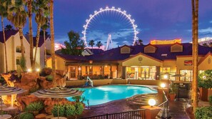 Ein Hotel mit Schwimmbad, Palmen und einem Riesenrad im Hintergrund.