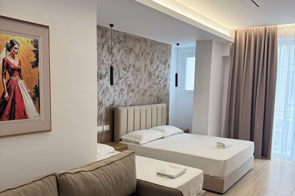 A modern hotel room with a large bed, a sofa, a painting, and a marble wall.