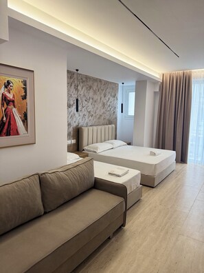 A modern hotel room with a large bed, a sofa, a painting, and a marble wall. - Hotel Moonlight (Vlorë)