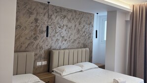A modern hotel room with two beds, a marble accent wall, and a minimalist design. - Hotel Moonlight (Vlorë)