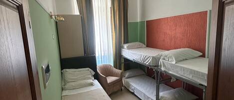 Una habitación con dos camas individuales, una litera, una silla y una ventana con cortinas.