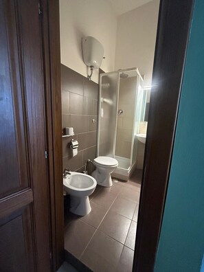 A bathroom with two toilets, a bidet, a shower, and a towel rack. - San Lorenzo One (Rome)