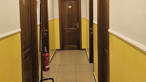 Un couloir étroit avec des portes en bois, un extincteur et un appareil de climatisation fixé au mur.