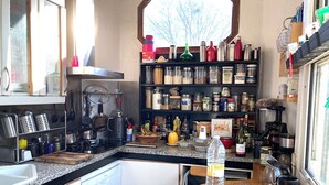 Une cuisine de taille réduite, dotée d’un plan de travail en granit, de meubles blancs et d’une fenêtre située au-dessus de l’évier.