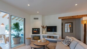 A modern living room with a sofa, a round coffee table, a TV, and a fireplace.