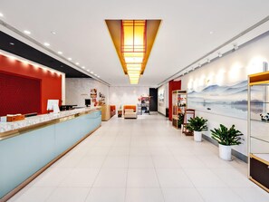 A hotel lobby with a reception desk, seating area, and a wall with a scenic mural. - Jinjiang Inn (Beijing)