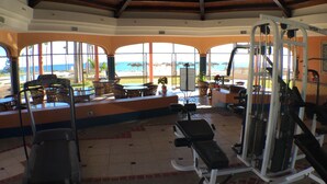 A gym with exercise equipment, a treadmill, and a view of the beach. - RockyCondo - Princesa A-407 Beach Front 2 Bed 2 Bath Condo (Puerto Penasco)