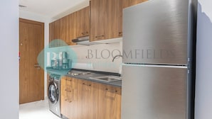Una cocina moderna con armarios de madera, un refrigerador de acero inoxidable y una lavadora integrada.