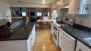 Una cocina amplia con piso de madera, muebles blancos y una isla central con fregadero.