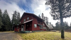Una casa de madera roja con porche, rodeada de árboles.