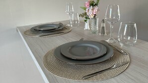 A dining table set with plates, cutlery, and glassware, accompanied by a decorative vase with flowers. - Apartment centrally located near Mambo beach Curacao (Willemstad)
