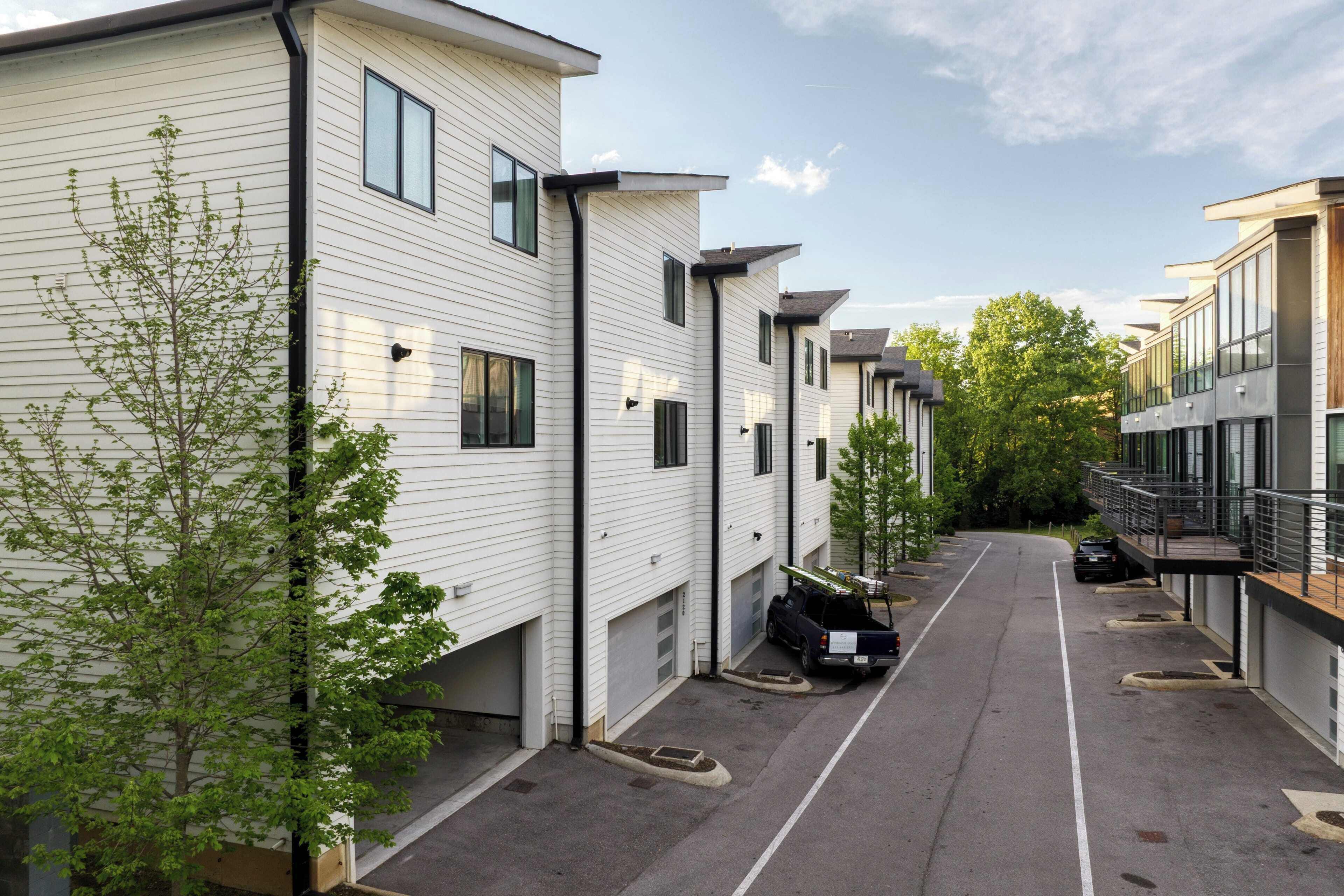 Une rangée d’immeubles d’appartements modernes, à un seul étage, avec un revêtement extérieur blanc et des bordures noires.
