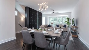 A modern dining area with a long table, grey chairs, and a contemporary chandelier. - Luxe 4bdr w/ Balcony & Parking, 10 Mins to Broadway 9th Avenue by Avantstay (Nashville)