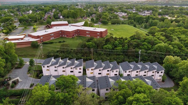 A residential area with a large brick building and a row of white houses with dark roofs. - Luxe 4bdr w/ Balcony & Parking, 10 Mins to Broadway 9th Avenue by Avantstay (Nashville)