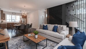 A modern living room with a sofa, coffee table, and dining area. - Luxe 4bdr w/ Balcony & Parking, 10 Mins to Broadway 9th Avenue by Avantstay (Nashville)