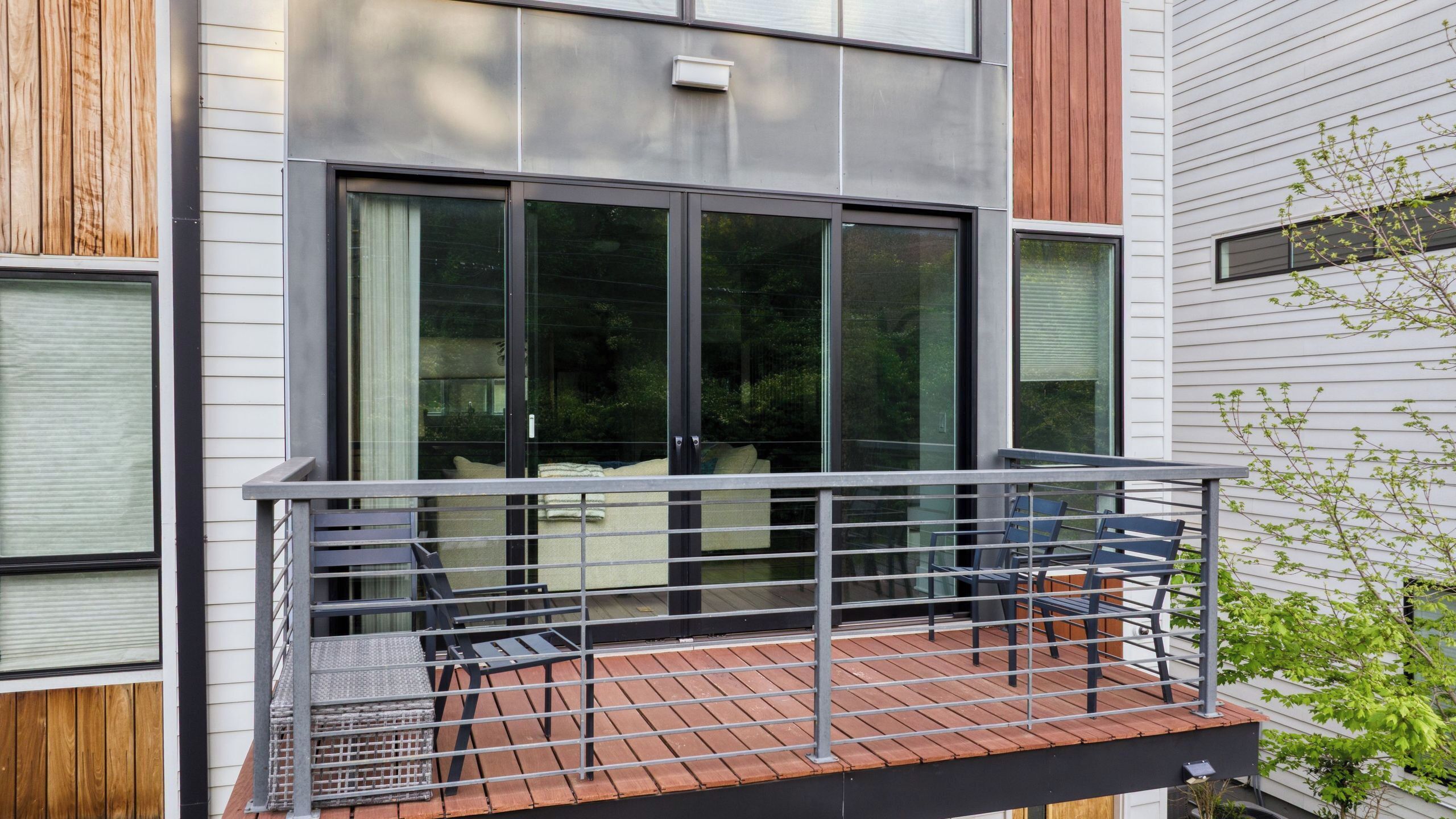 Ein modernes Gebäude mit Balkon, großen Fenstern und einem Metallgeländer.
