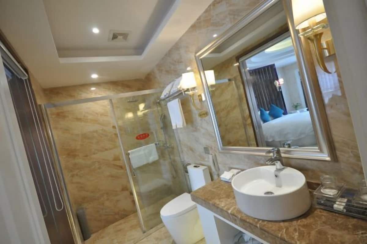 A modern bathroom with a glass shower enclosure, a white sink, and a large mirror.