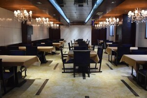 Un restaurante con cabinas y mesas, candelabros y suelo de mármol.