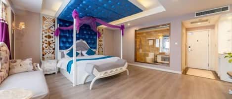 Un dormitorio moderno con cama, zona de estar y un ventanal grande.
