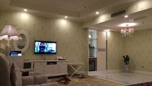 A room with a television, a white cabinet, a patterned carpet, and a chandelier. - Lanzuan Hotel (Ankang)