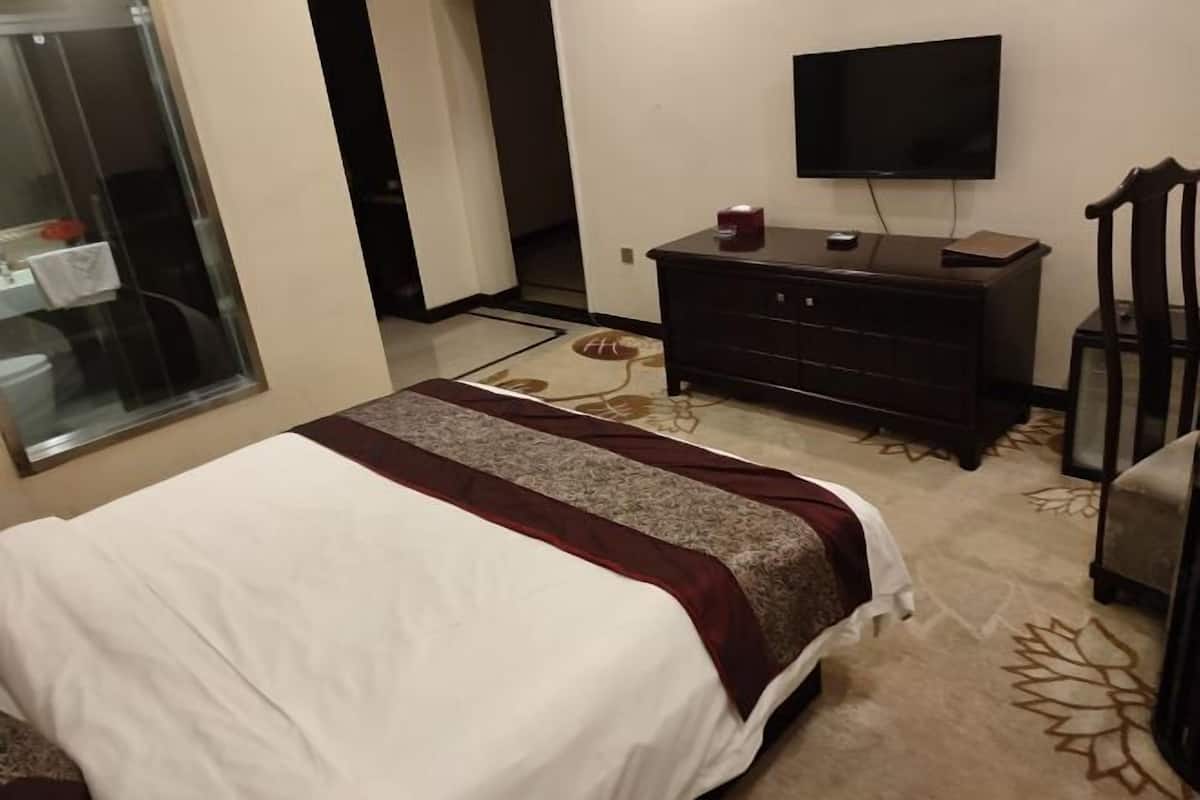 A hotel room with a bed, a television, a dresser, and a chair.