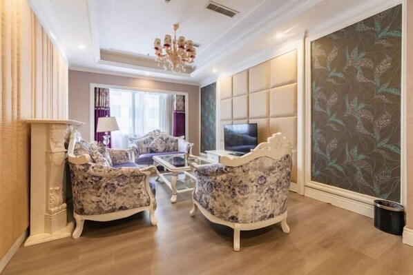 A living room with a sofa set, a television, and a decorative wall panel. - Lanzuan Hotel (Ankang)