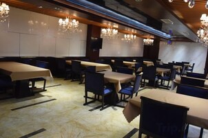 Un restaurante con varias mesas y sillas, candelabros y un piso de mármol.