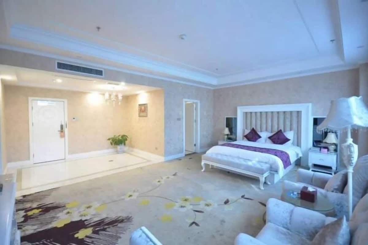 A hotel room with a bed, bedside table, lamp, and a floral carpet.