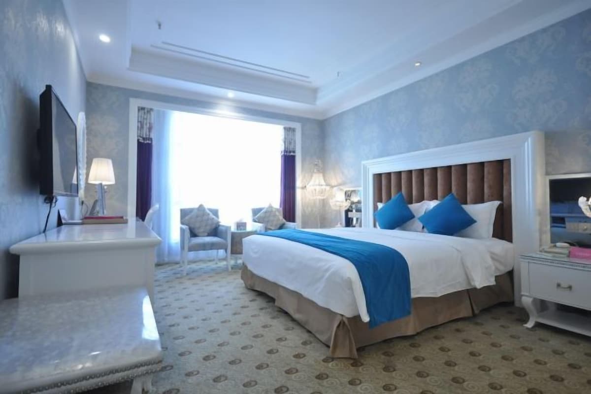 A hotel room with a large bed, bedside tables, a desk, and a chair.