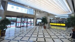 A hotel lobby with a checkered floor, glass doors, a reception desk, and potted plants. - Lanzuan Hotel (Ankang)