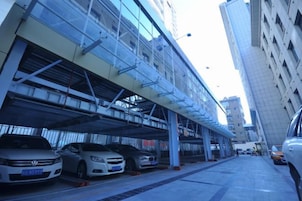 Una estructura de estacionamiento con varios niveles y varios coches aparcados bajo una zona cubierta.