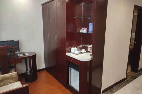 A compact room with a wardrobe, a small table with a chair, and a built-in sink with toiletries. - Lanzuan Hotel (Ankang)