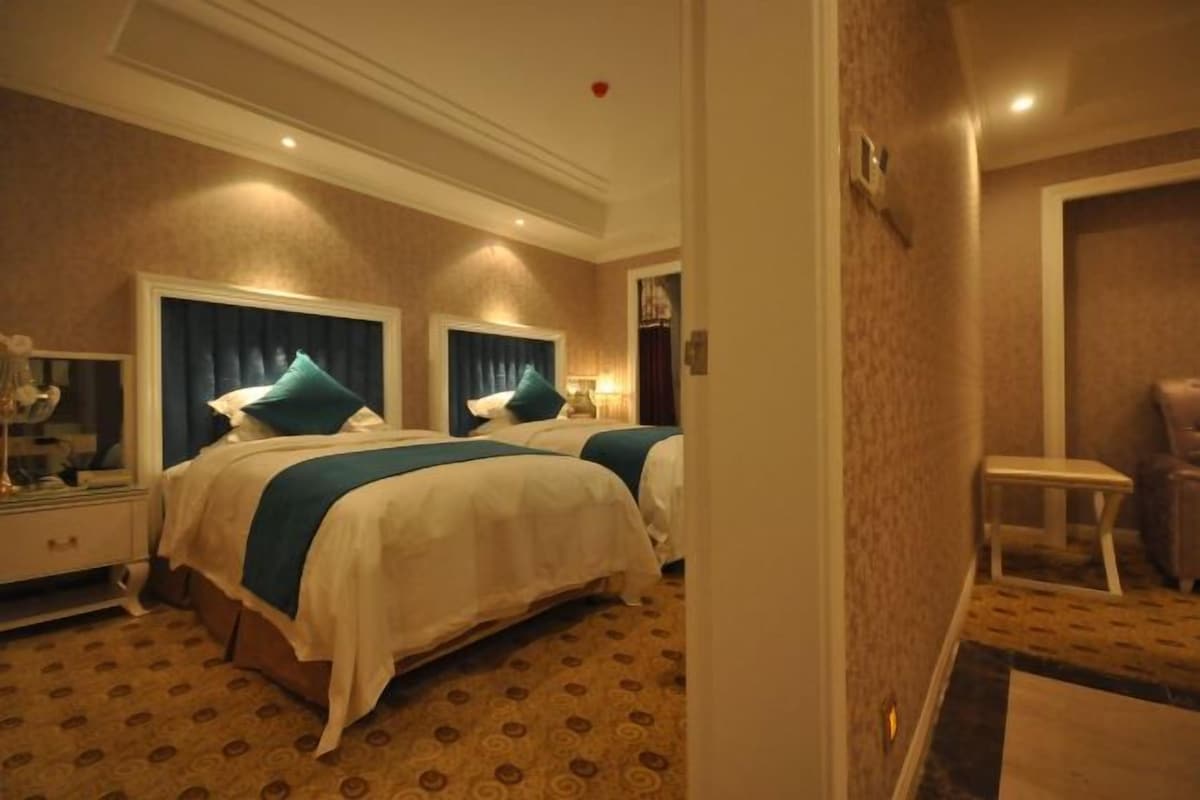 A hotel room with two beds, a nightstand, a desk, and a chair.