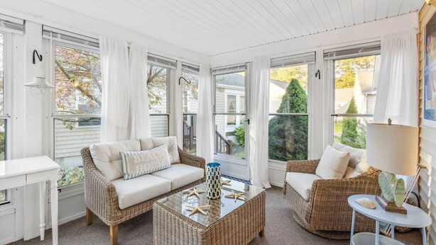 A sunlit room with wicker furniture, a glass coffee table, and a white desk. - Sweet Beach Dreams (Wells)