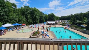 A swimming pool area with lounge chairs and umbrellas, surrounded by trees. - Sweet Beach Dreams (Wells)