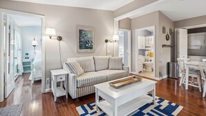 A modern living room with a striped sofa, a white coffee table, and a ceiling fan. - Sweet Beach Dreams (Wells)