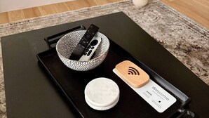 A black tray with a white bowl, a remote control, a white lid, and a wooden coaster with a Wi-Fi symbol. - Hoosier HQ: Sleek 3-Bed Near IU (Bloomington)