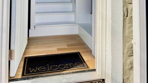 A staircase leading to a dark interior, with a 'Welcome' mat at the bottom. - Hoosier HQ: Sleek 3-Bed Near IU (Bloomington)