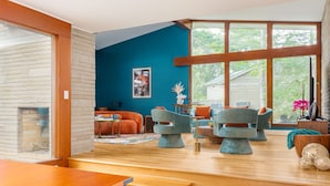 A modern living room with a large window, a fireplace, and a variety of seating options.