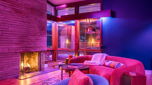 A modern living room with a fireplace, large windows, and a cozy seating area.