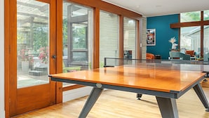 A spacious room with a ping pong table, large windows, and a view of the outdoors.