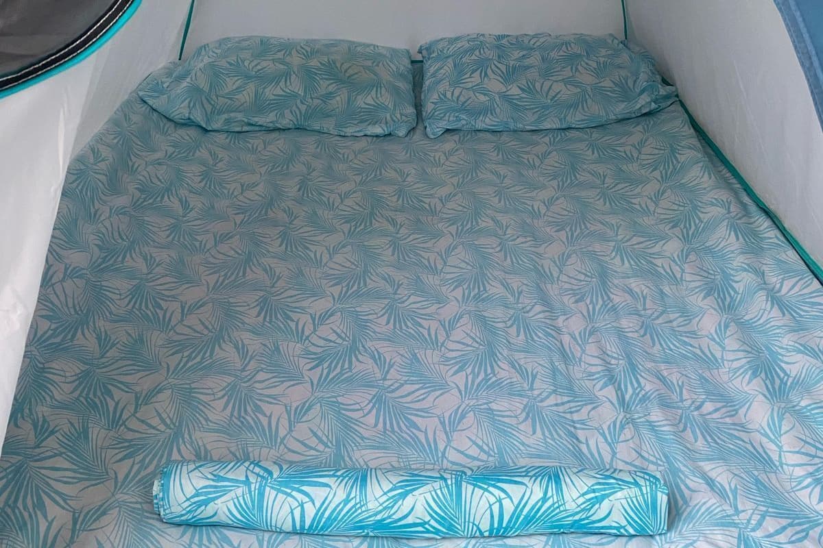 A tent with a bed inside, featuring a leaf pattern on the bedding.