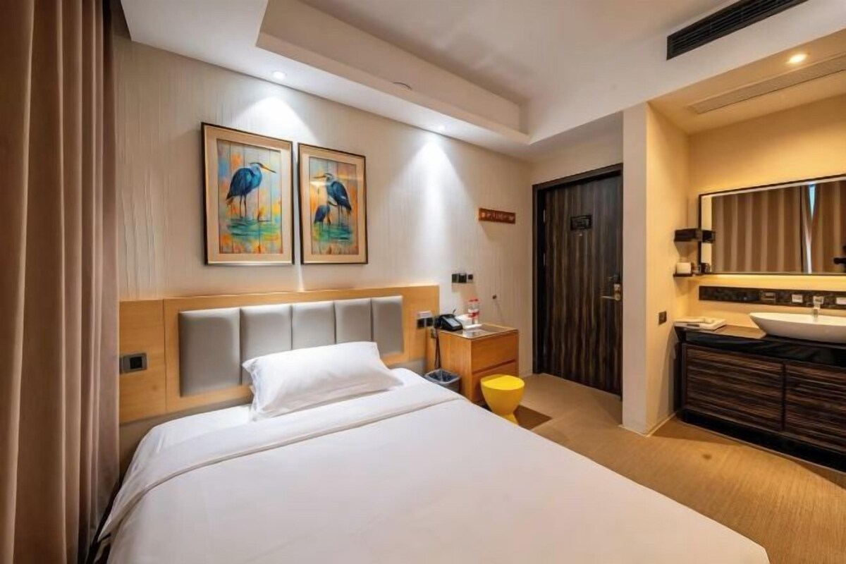 Une chambre d’hôtel avec un lit, une table de chevet, un miroir, un lavabo et des œuvres d’art accrochées au mur.