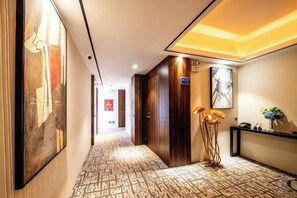 A hotel hallway with patterned carpet, wooden doors, and artwork on the walls. - Tingquan Meiyu Hotel (Jinhua Vocational and Technical College) (Jinhua)
