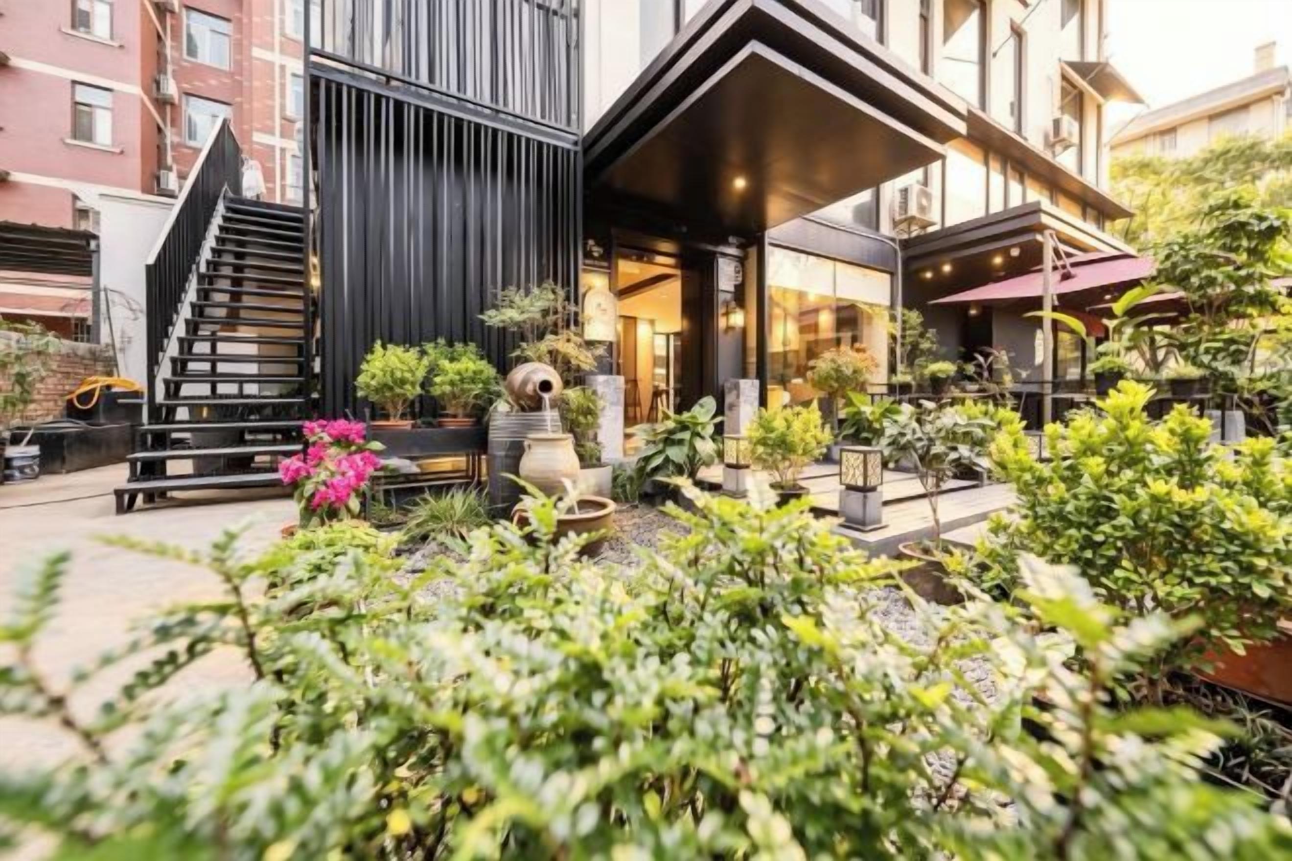 A modern building with a black facade, a staircase, and a covered outdoor seating area with plants.