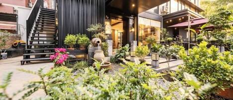 A modern building with a black facade, a staircase, and a covered outdoor seating area with plants.