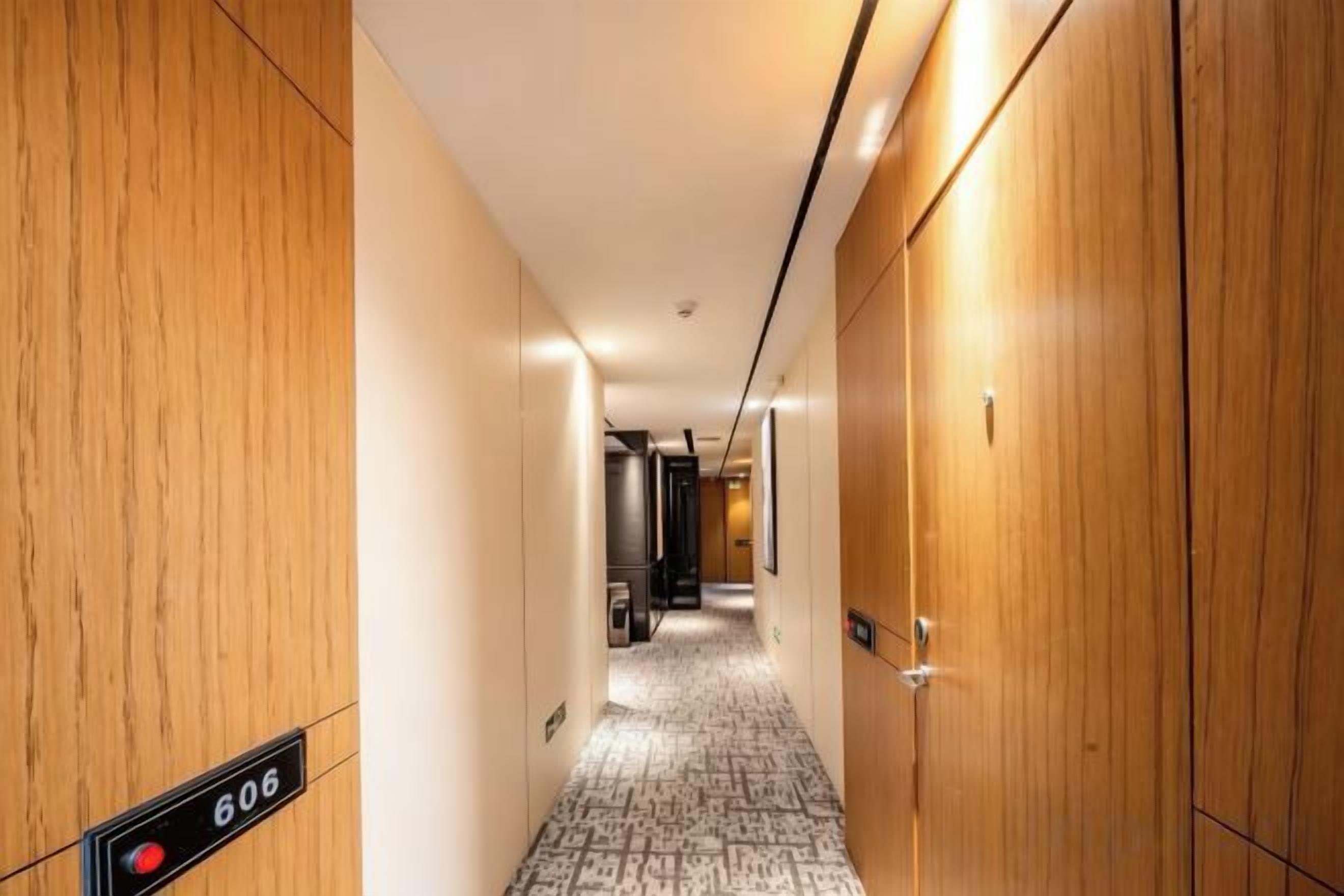 Een hotelgang met houten wanden, een vloerbedekking en een bordje met kamer nummer 606.