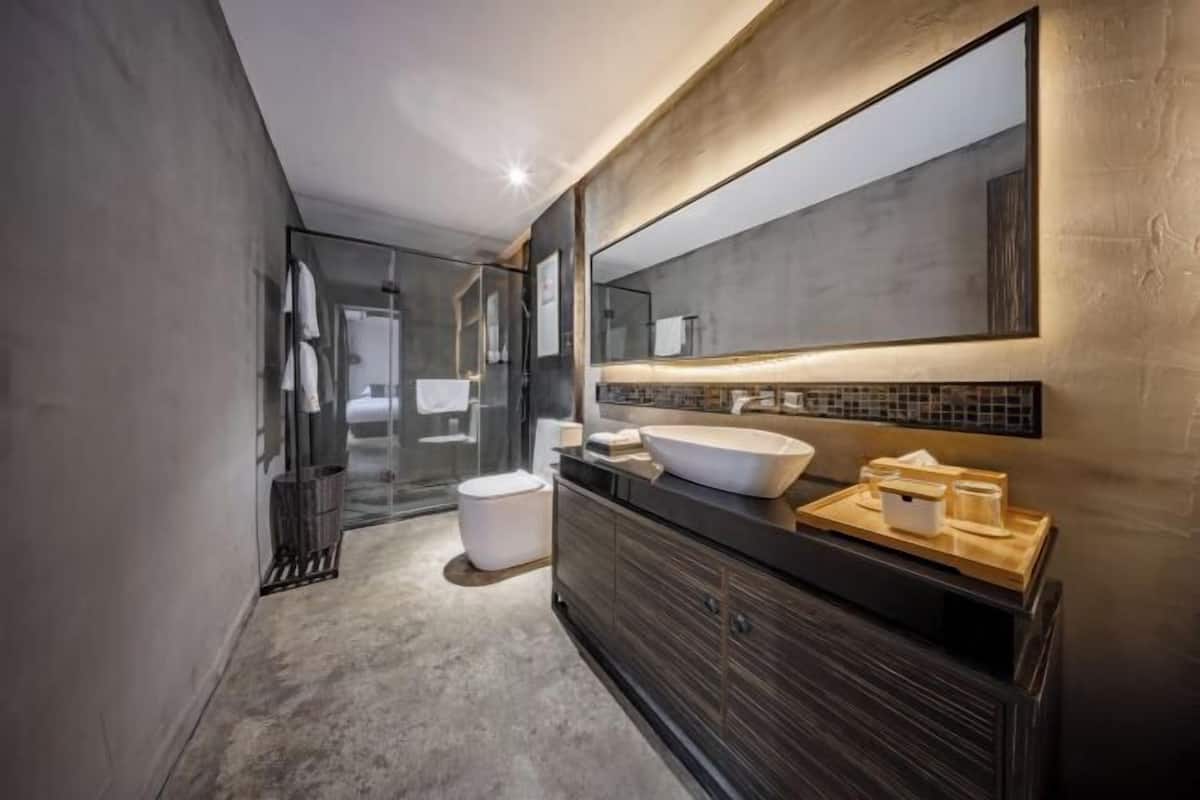 Un baño moderno con un espejo grande, un lavabo sobre encimera y un mueble de tocador de madera oscura.