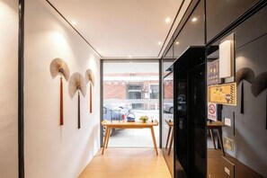 Un pasillo con una mesa de madera, un ventilador y vistas al exterior.